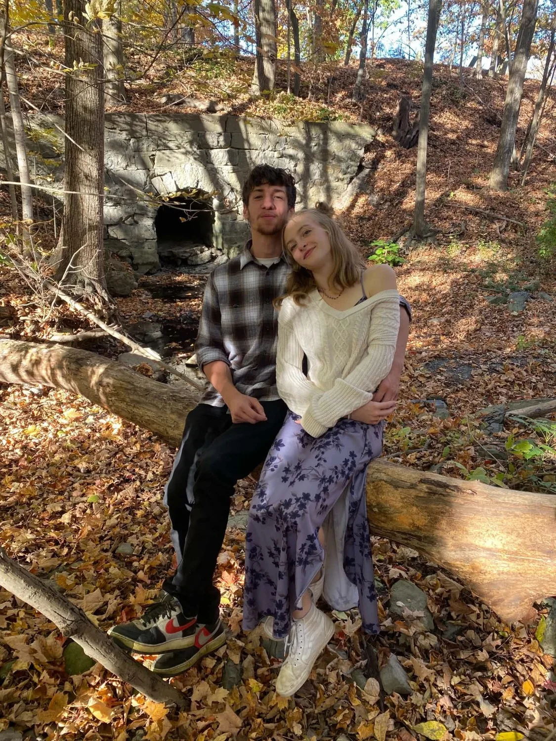 Nathan and Piper sitting together among autumn leaves